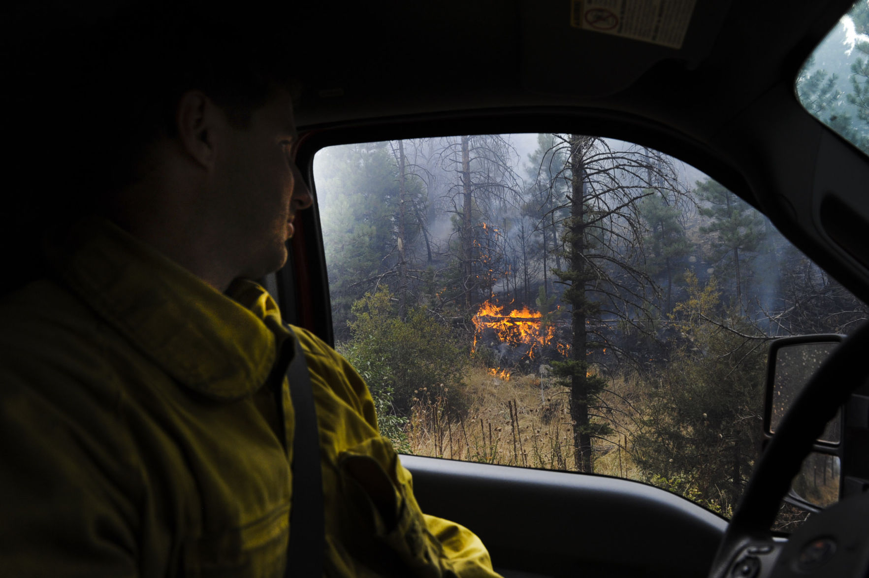 Montana City Fire assistant chief Lyn Stimpson peers out his window at fire burning just off Holmes Gulch Road Thursday evening.